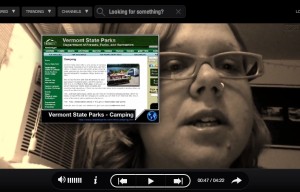 A video closeup of a woman's face. She's wearing glasses, and next to her on-screen is a preview of the Vermont State Parks website.