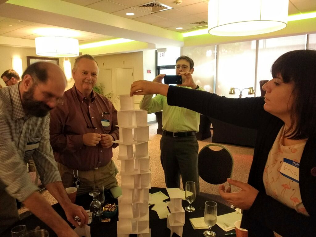 A photo showing a team of educators building a tower out of index cards.