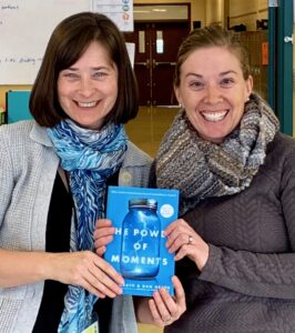 Host Jeanie Phillips, left and guest Rachel Mark, right hold a copy of the book The Power of Moments