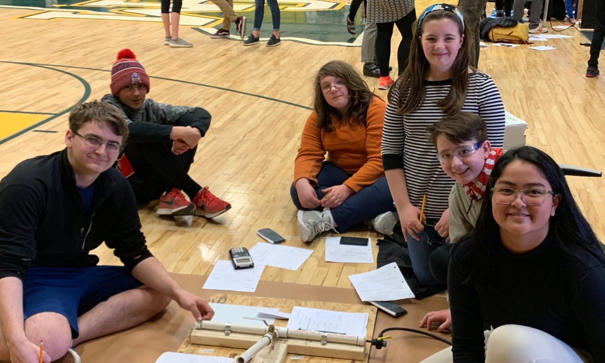 Students work together on the gym floor building a catapult