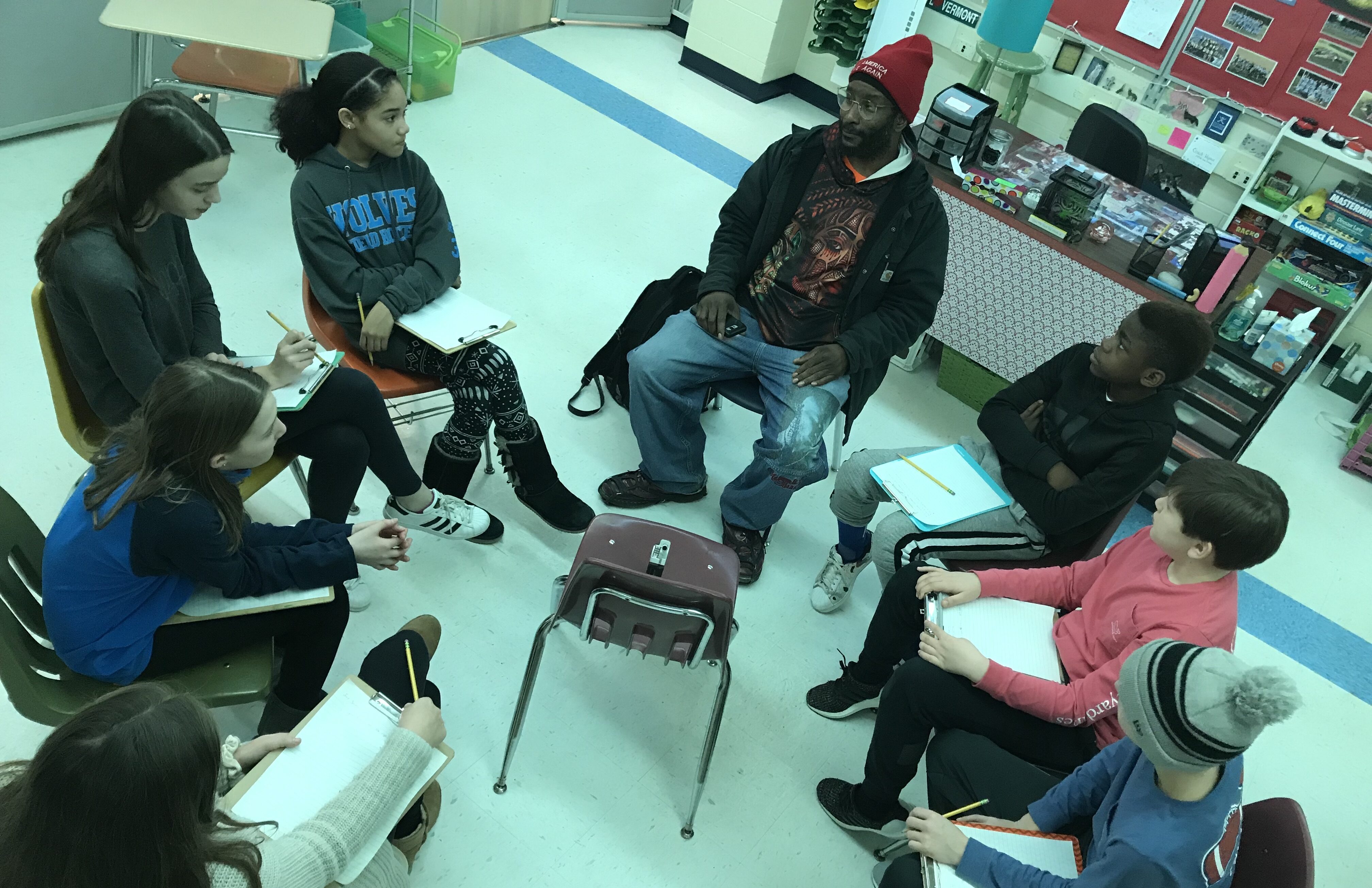 A group of students sits in a circle with an adult