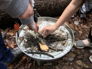 hands arranging fire materials in a steel pan