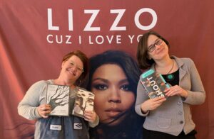 Meg Falby and Jeanie Phillips in front of a giant mural of Lizzo