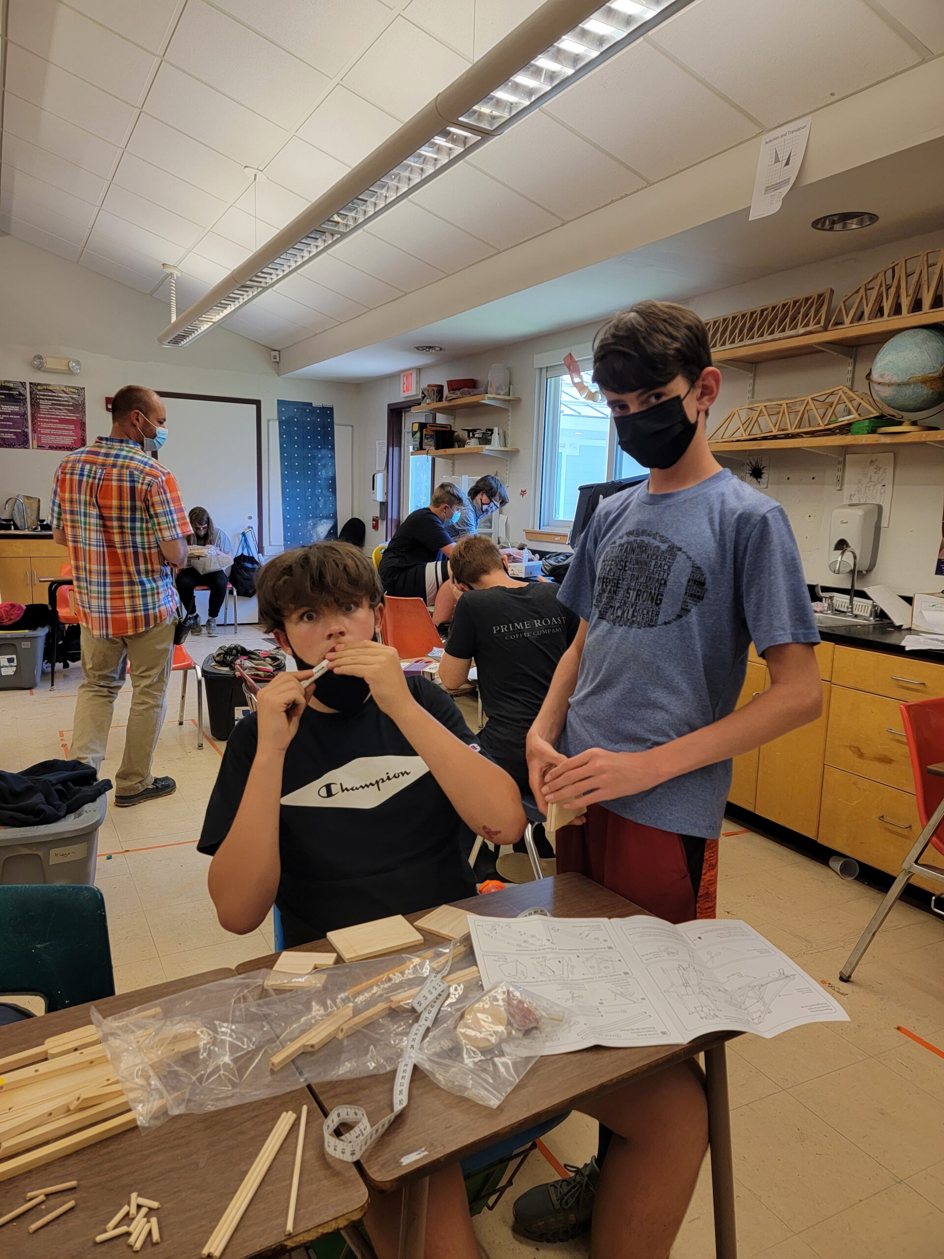 Two masked students pause in their work