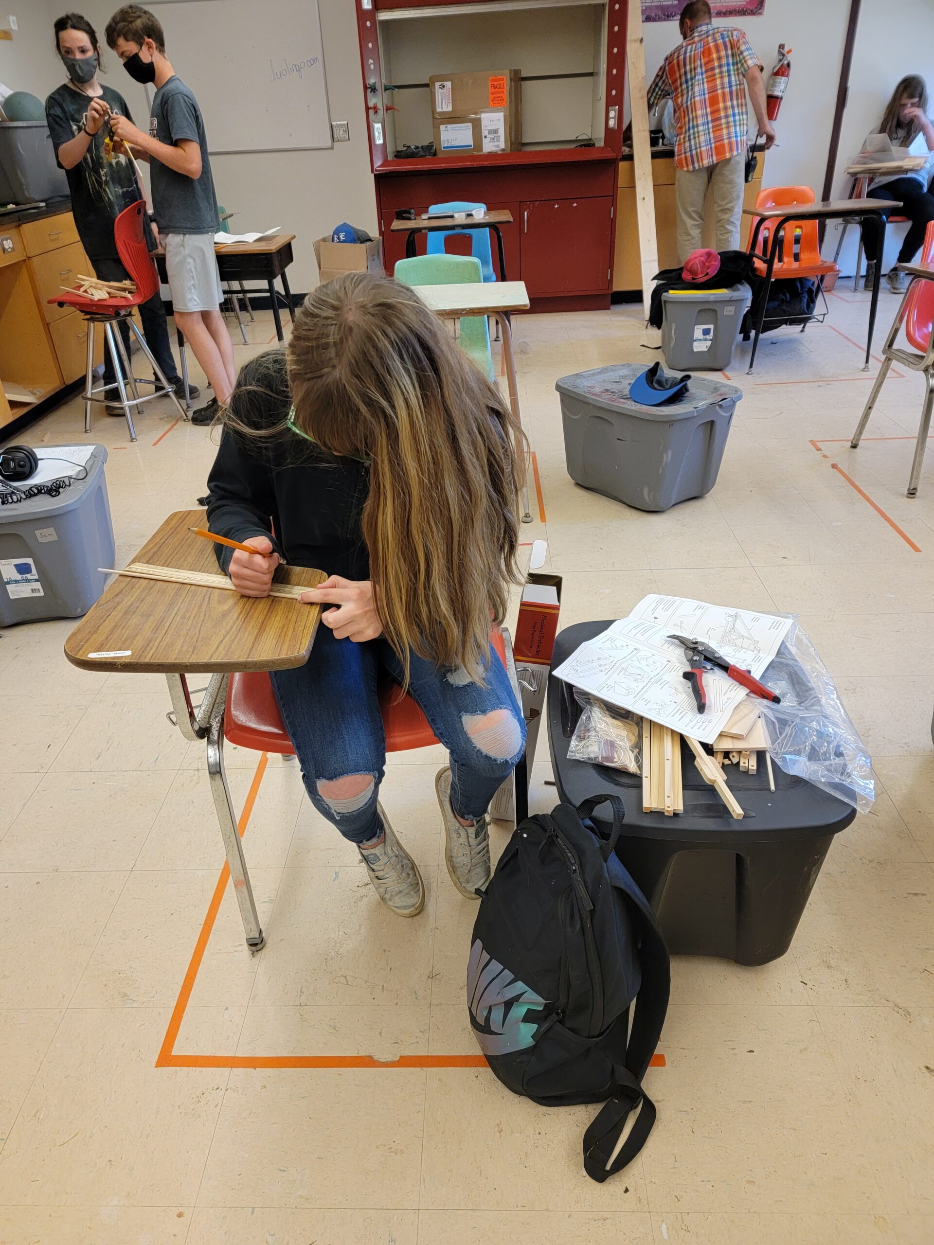 A masked student works at a desk
