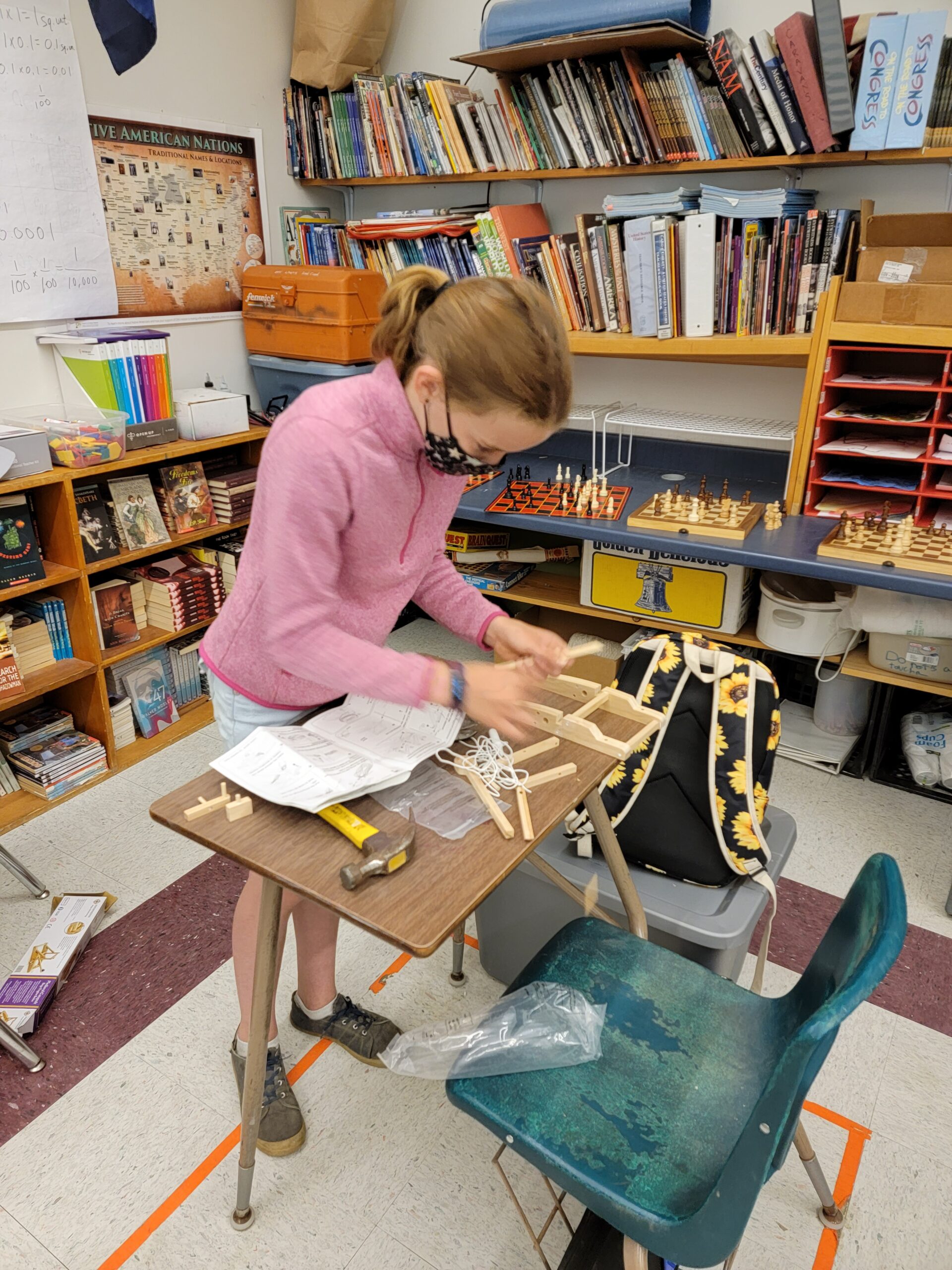 A masked student works on wood