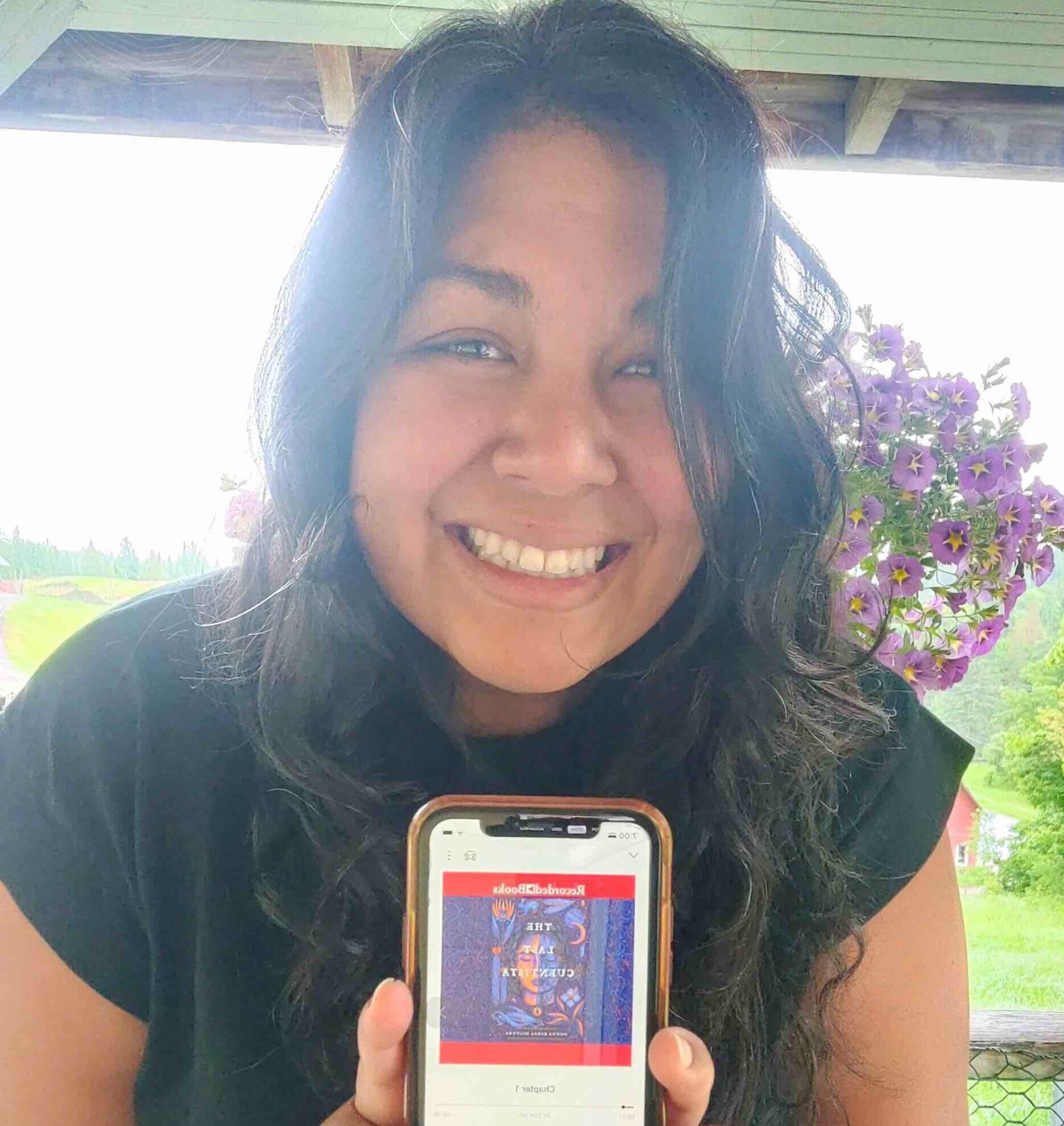 Ornella Matta Figuero holds up her phone showing the audiobook The Last Cuentista