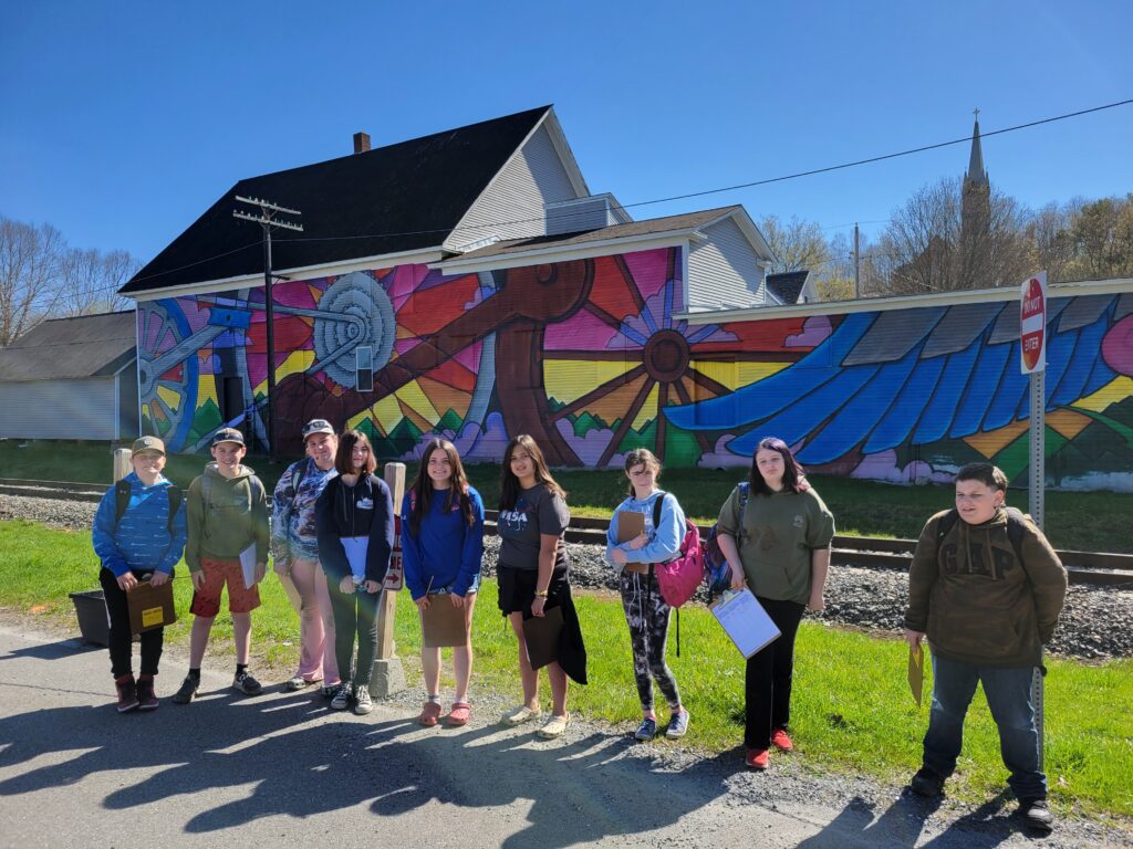 A group of students stand in front of a mural