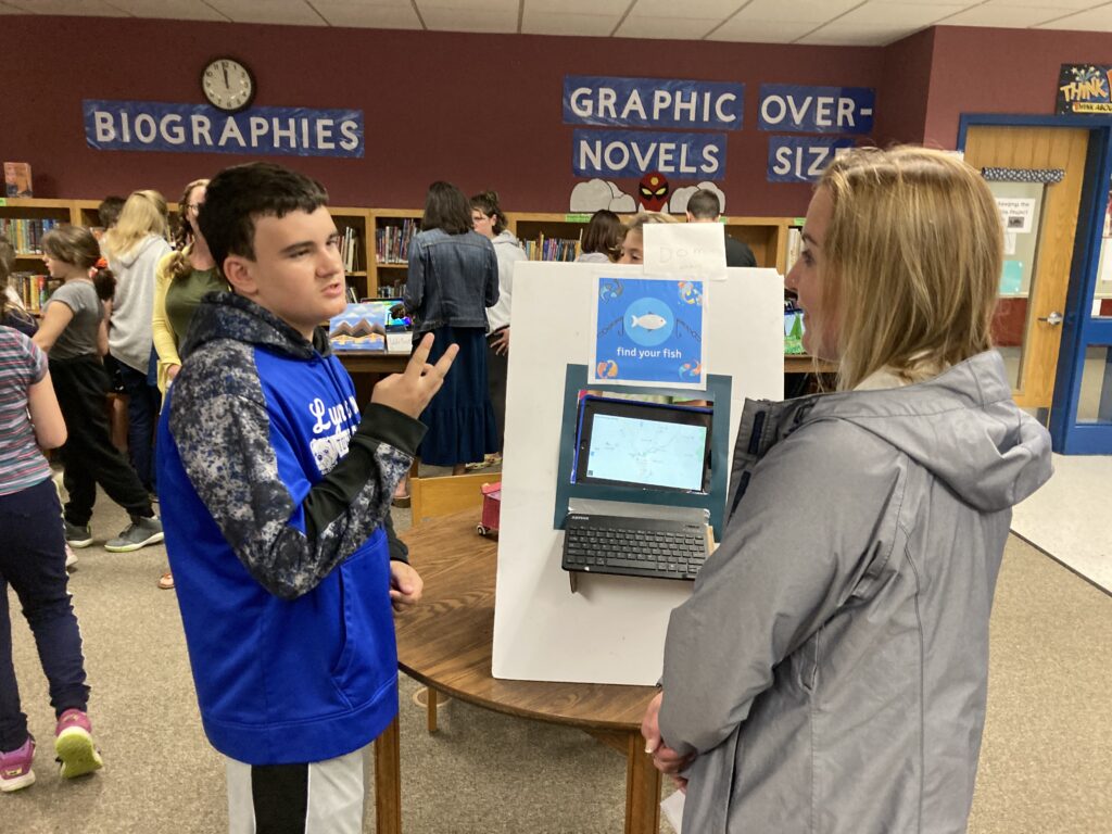 A student explains a project to an adult