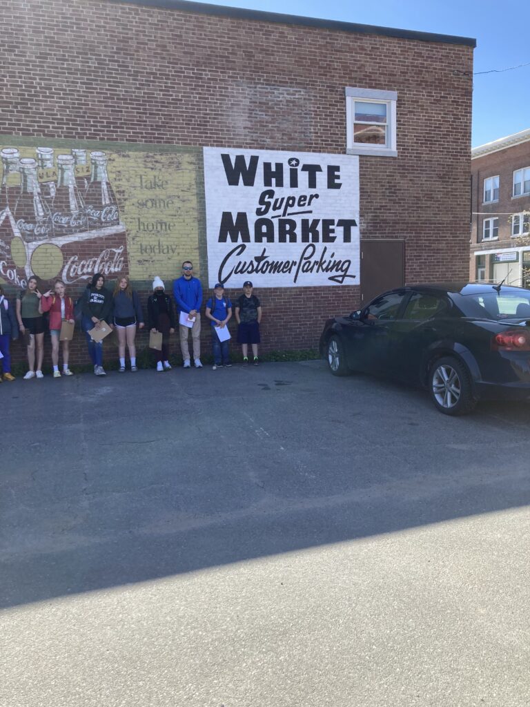 A group of students stand along the wall of a building