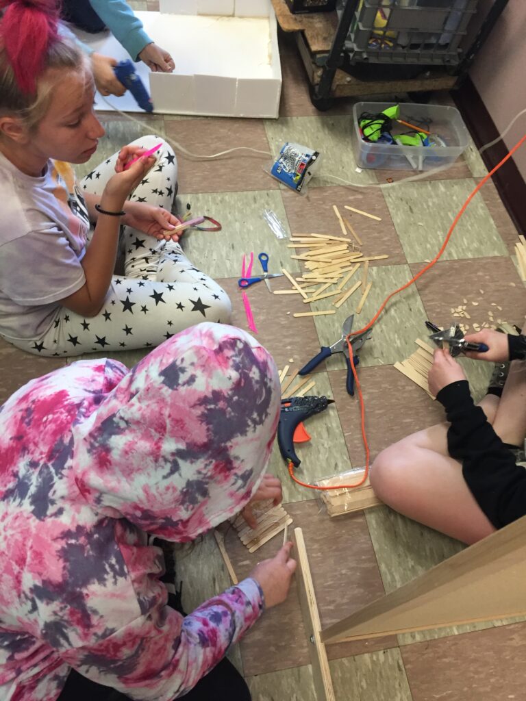 A group of students work together with popsicle sticks