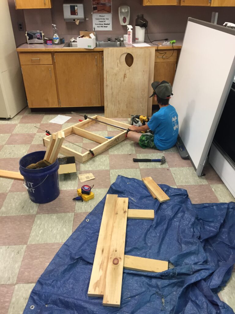 A student sits in a classroom doing woodworking