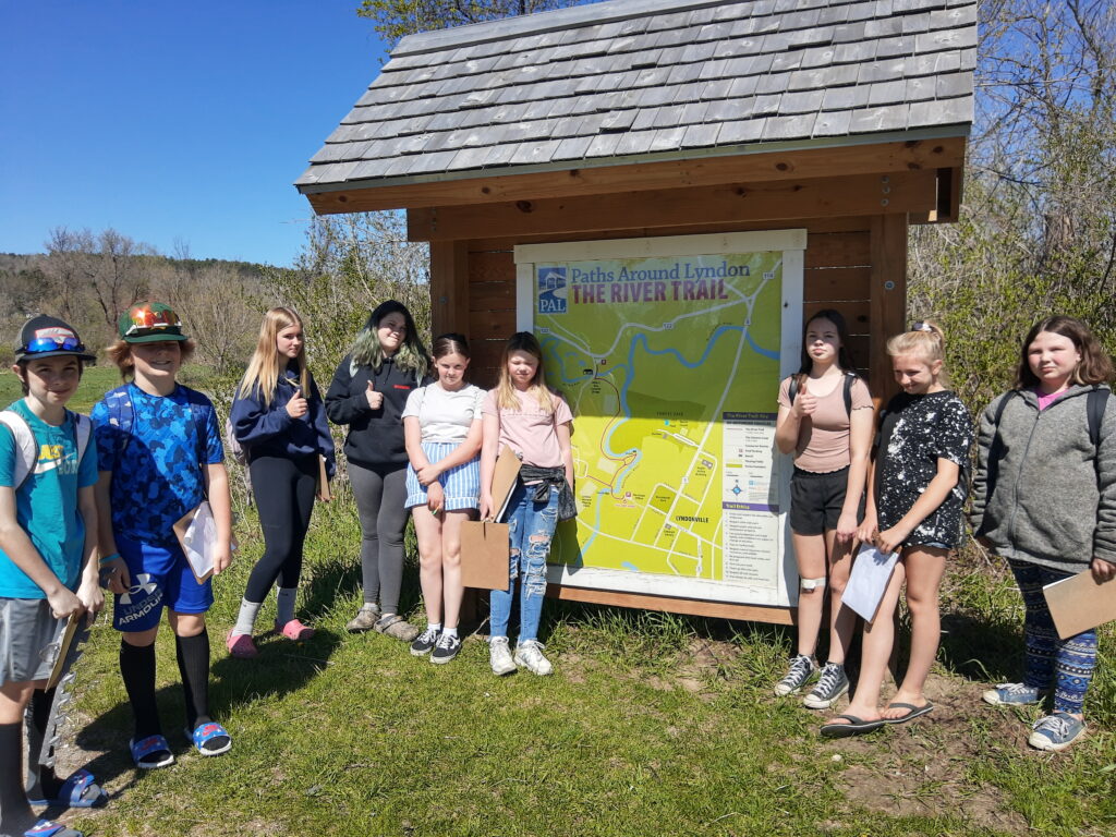 A group of students stand next to a map