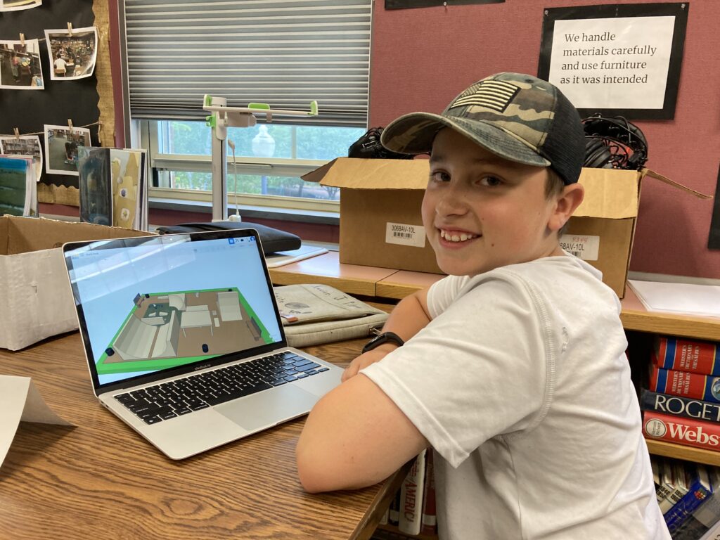 A student poses by a laptop