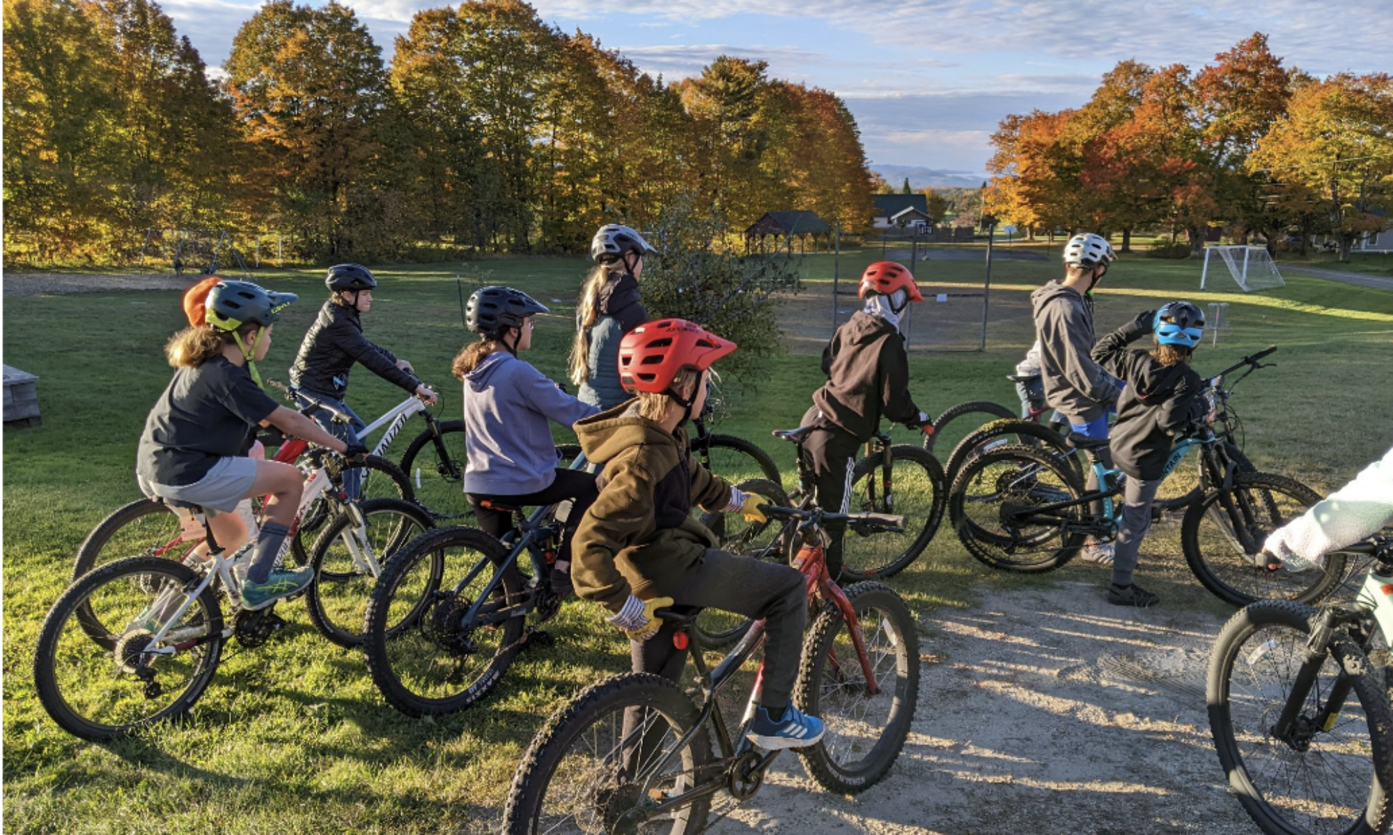 Students on mountain bikes with soccer goal in the background.