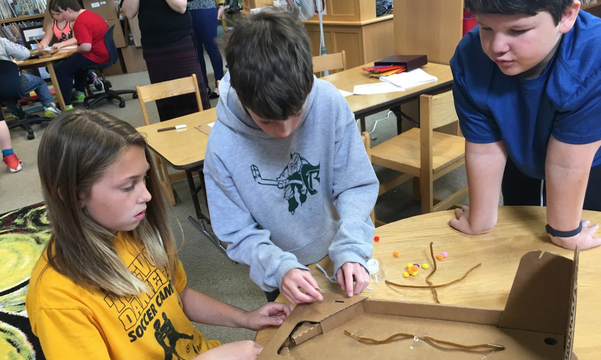 A trio of students prototype a cardboard pinball game