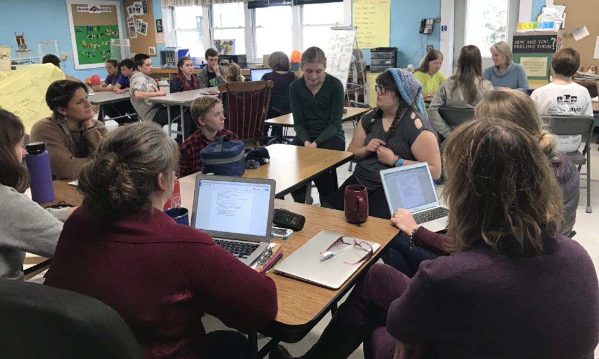 Students gather in a classroom to explain to adults