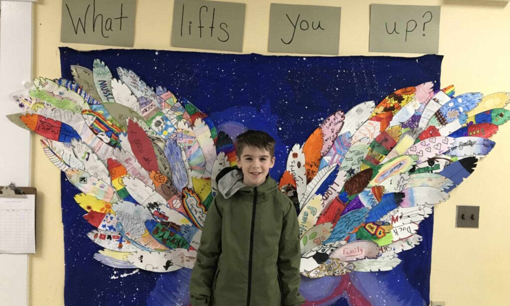 A teen boy stands in front of a school mural that seemingly gives him wings